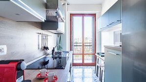Una cocina moderna con cafetera espresso integrada, un lavamanos y una ventana con vistas a un balcón.