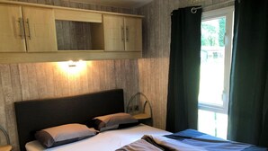 Una camera da letto con un letto, comodini, un tavolino e una finestra con tende.