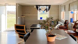 A modern interior with a long table, chairs, a potted plant, and a view through a window. - 4 Star Holiday Home in Burgsvik (Burgsvik)