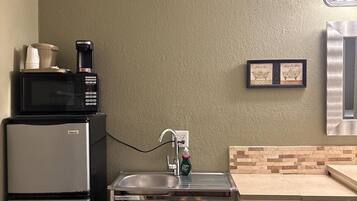 A compact kitchenette with a refrigerator, microwave, sink, and a small countertop.