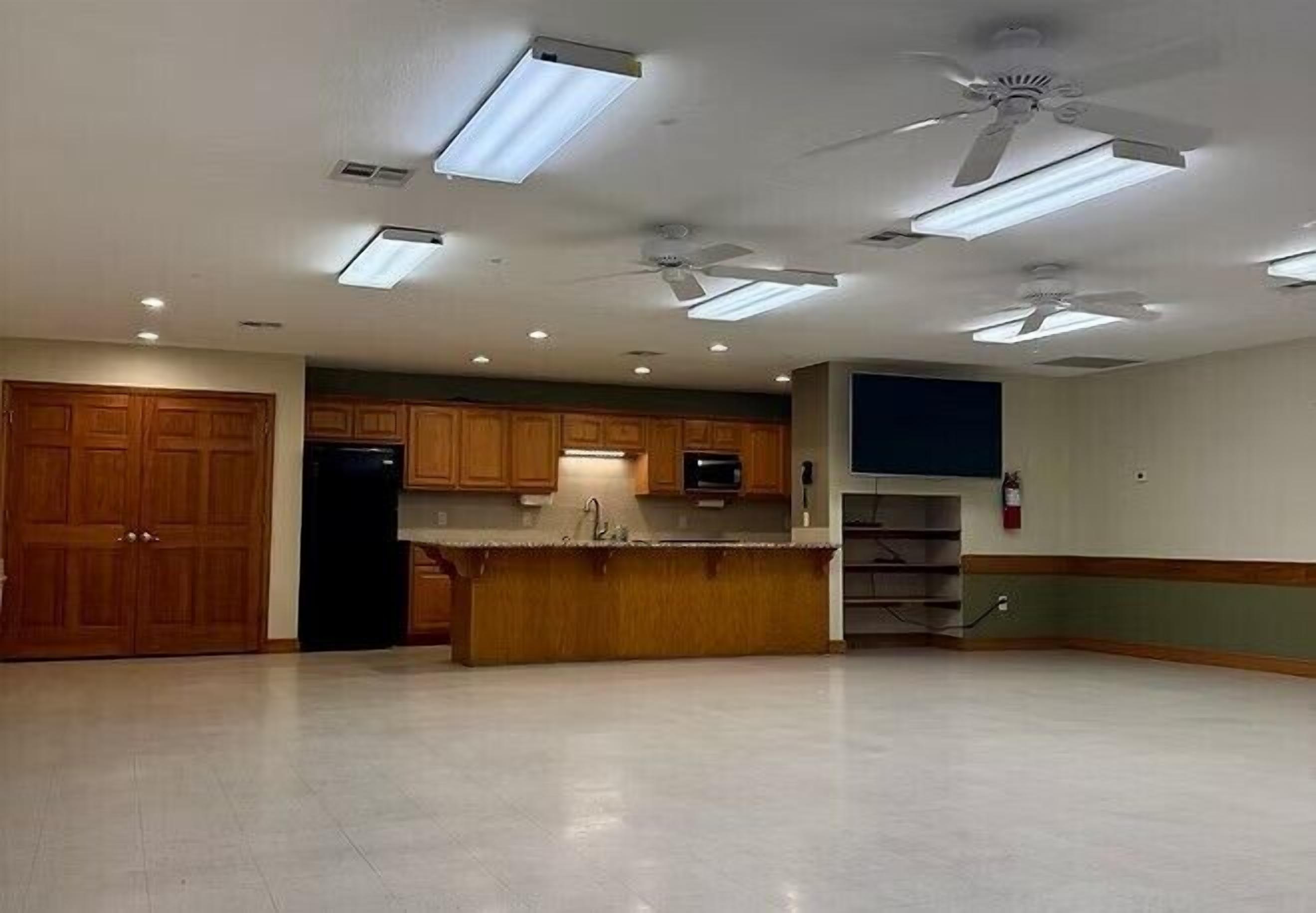 A spacious kitchen with wooden cabinets, a central island, and ceiling fans.