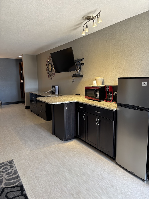 A modern kitchen with a flat-screen TV, a microwave, a refrigerator, and a coffee maker. - Twin Lakes Inn and RV (Stigler)