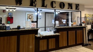 Una recepción con un cartel que dice 'WELCOME', un extintor y una planta pequeña en el mostrador.