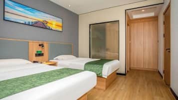 Habitación de hotel con dos camas, un armario de madera, un cuadro en la pared y una puerta que da a otra habitación.