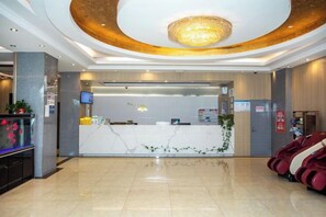 Ein Hotel-Empfangsbereich mit modernem Design, einer Rezeption, einem Fernseher und einem Massagesessel.