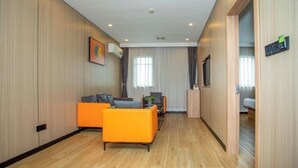 Un salon moderne avec des murs recouverts de panneaux en bois, un ensemble de canapés, une table basse et un téléviseur.