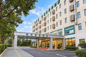 A hotel entrance with a covered walkway, a parking area, and a sign indicating a restaurant. - GreenTree Inn (Shanghai Fengxian Xidu) (Shanghai)