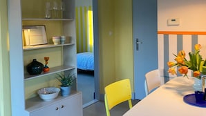 A dining area with a white table, yellow chairs, and a blue vase with flowers. - Holiday Home in Noordwijkerhout Near Lake (Noordwijkerhout)