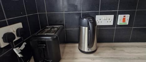 A kitchen with a toaster, kettle, and a painting on the wall.