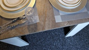 Ein Tisch für vier Personen gedeckt mit goldverzerrten Tellern, klarem Glas und gefaltetem Servietten.