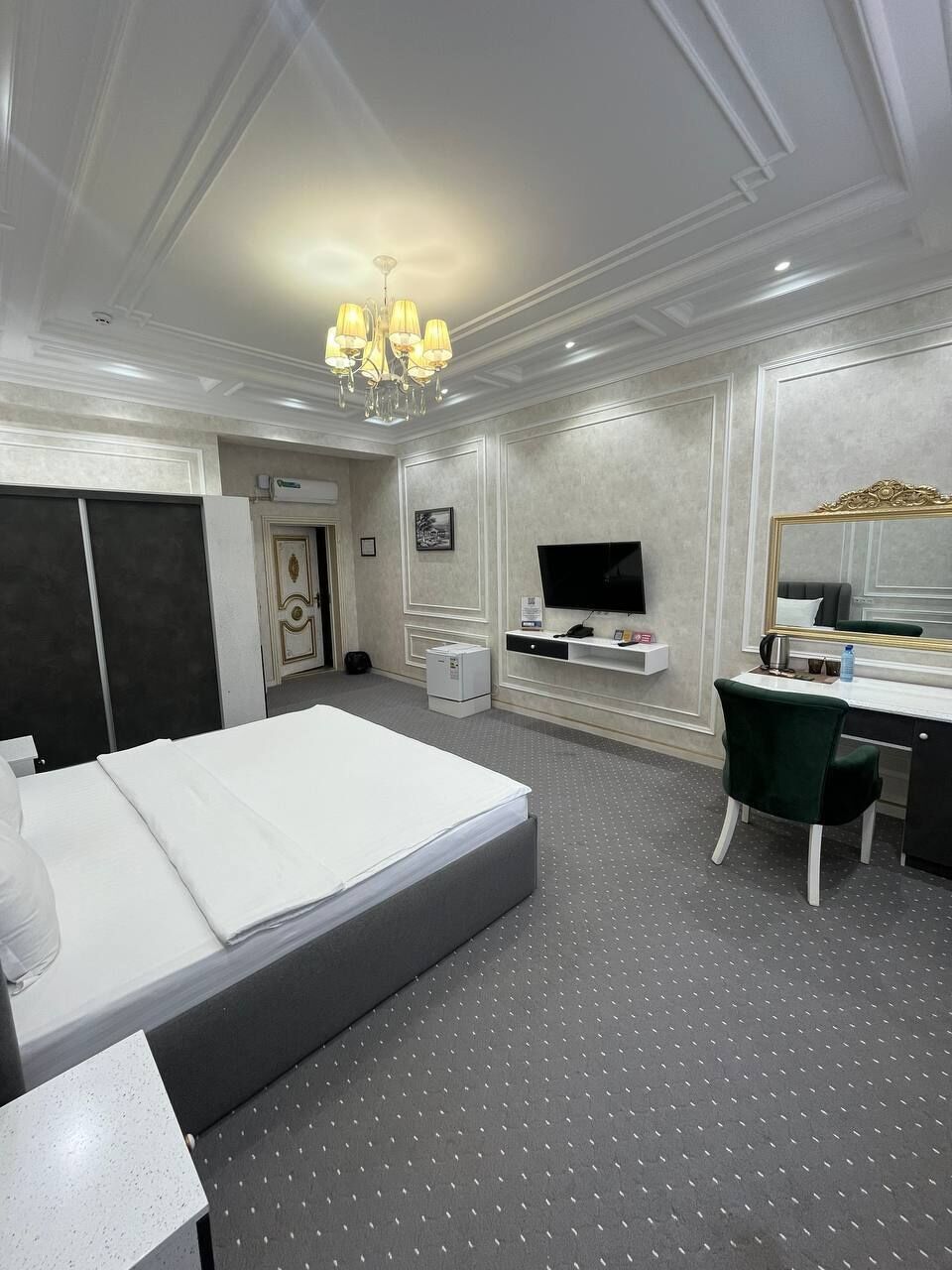 Habitación de hotel con una cama grande, un escritorio con silla, un televisor y un espejo.