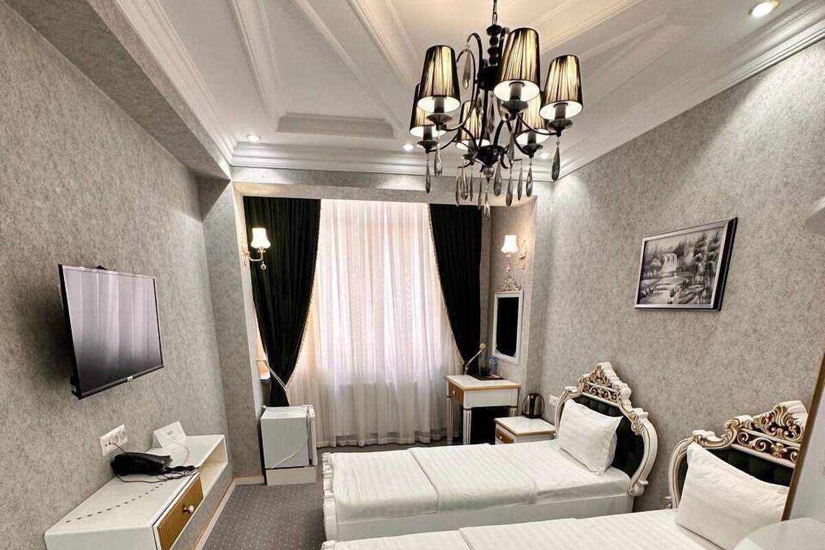 Habitación de hotel con dos camas, televisión, escritorio, tocador y candelabro.