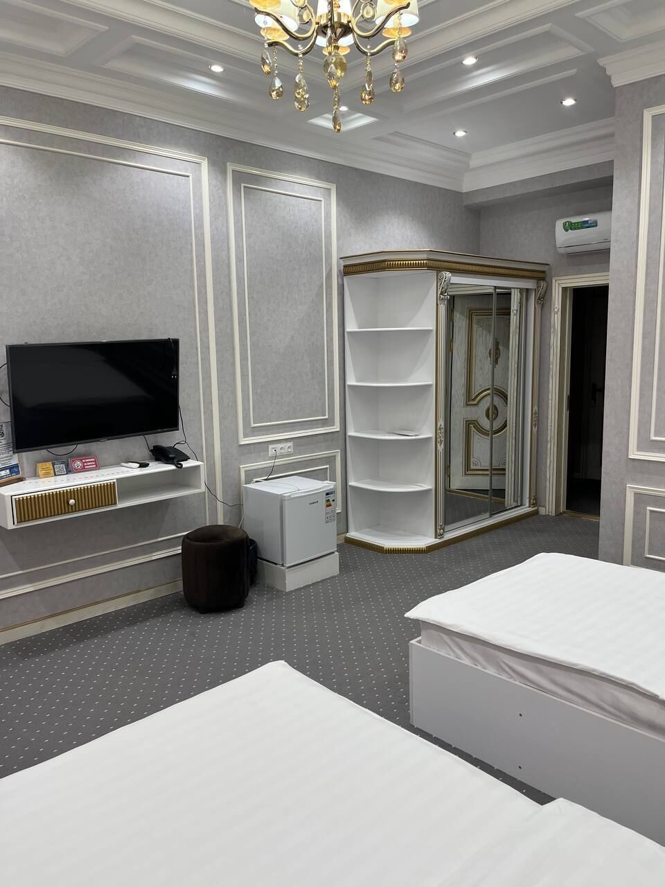 Habitación de hotel con televisor de pantalla plana grande, tocador con espejo, vestidor y dos camas.