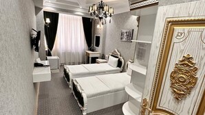 Hotellihuone, jossa on suuri sänky, työpöytä, tuoli, kattokruunu ja vaatekaappi.