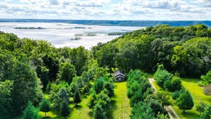 En hytte omgivet af tæt skov med en sø i baggrunden.
