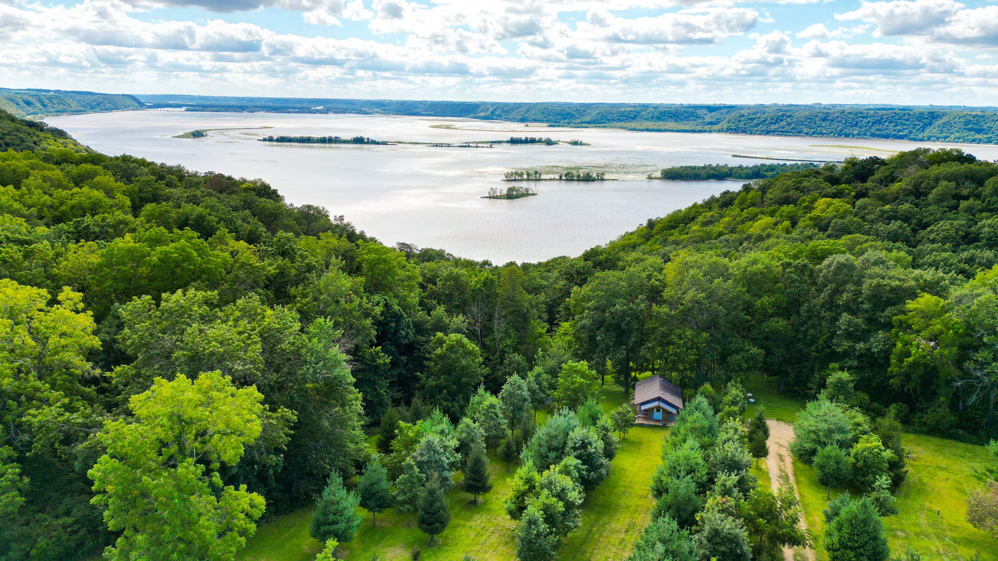 Una cabaña rodeada de un bosque frondoso y un lago extenso.