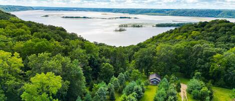 Una cabaña rodeada de un bosque frondoso y un lago extenso.