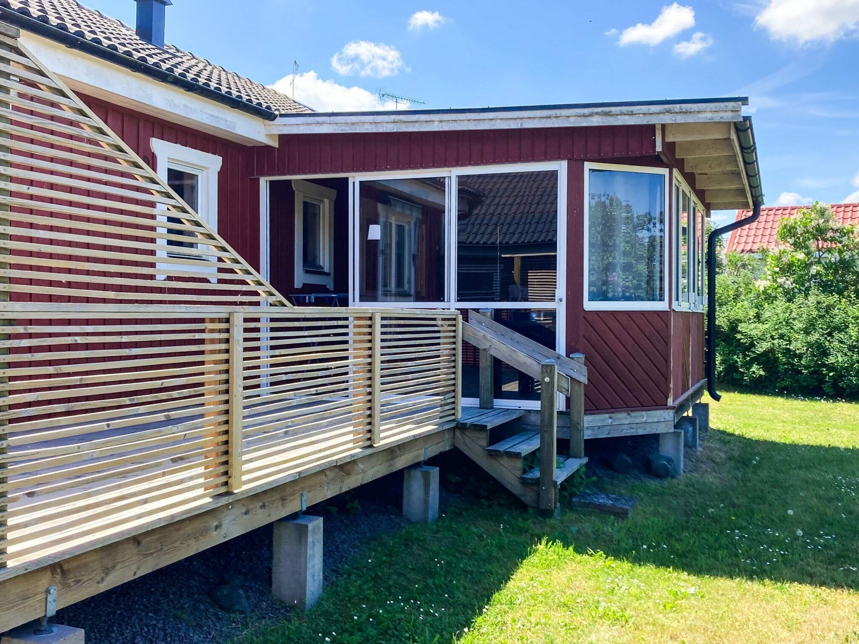 A red wooden house with a porch and a wooden deck.