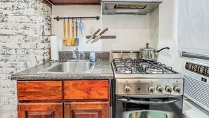A kitchen with wooden cabinets, a stainless steel stove, a microwave, and a sink. - 183 Orchard St (New York)