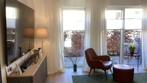 A modern living room with a large flat-screen TV, a sofa, a coffee table, and a view of a balcony with bicycles. - 4 Star Holiday Home in Vedbaek (Vedbaek)