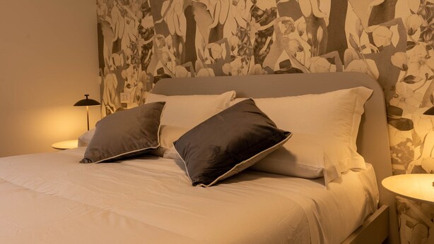 Una cama bien hecha con dos almohadas, un cabecero y dos lámparas de noche.