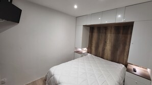 A bedroom with a bed, bedside tables, and a wardrobe. - Le 108: Ground floor apartment with large terrace on the seafront (Leucate)