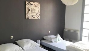 Een kamer met twee bedden, een wandlamp en een inspirerende quote op de muur.
