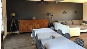 Een moderne woonkamer met een eethoek, een bank en een houten kast.
