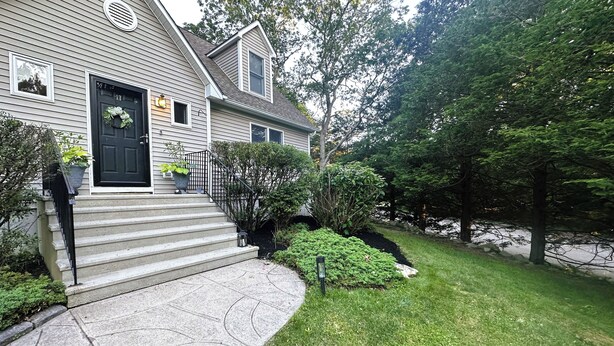 A two-story house with a front porch, a black door, and a mailbox.