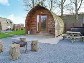 A wooden cabin with a porch, a barbecue grill, and picnic tables. - 1 bedroom accommodation in Kelk, near Driffield (Kelk, near Driffield)