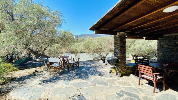 An outdoor patio with stone flooring, wooden furniture, and a stone pillar. - Cottage 100m from the beach (CT)