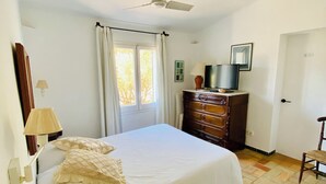 A bedroom with a bed, a dresser, a television, and a ceiling fan. - Cottage 100m from the beach (CT)