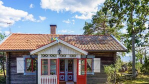 A wooden house with a red door, white trim, and a tiled roof. - 6 Person Holiday Home in Oskarshamn (Oskarshamn)