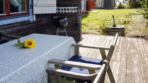 A wooden deck with a table and chairs, a barbecue grill, and a small garden area. - 6 Person Holiday Home in Oskarshamn (Oskarshamn)