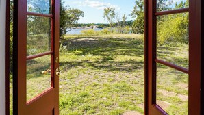 An open door leading to a grassy area with a lake and trees in the background. - 6 Person Holiday Home in Oskarshamn (Oskarshamn)