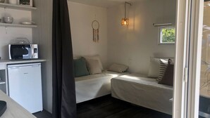 A compact room with a kitchenette, two beds, a dreamcatcher, and a hanging light fixture. - Lodge Near Antwerp With Nature Trails (Lille)