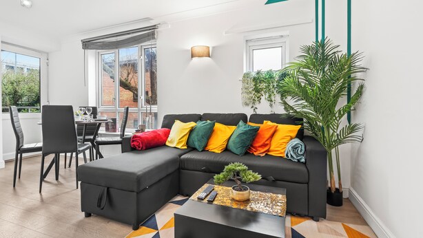 A modern living room with a sectional sofa, a coffee table, and a dining area with chairs and a table.