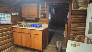 Una cocina rústica con armarios de madera, un lavamanos y un escurreplatos azul.