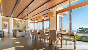 A spacious living area with a dining set, large windows, and a view of the outdoors.