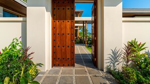 A modern entrance with a wooden door, a pathway, and surrounding greenery.