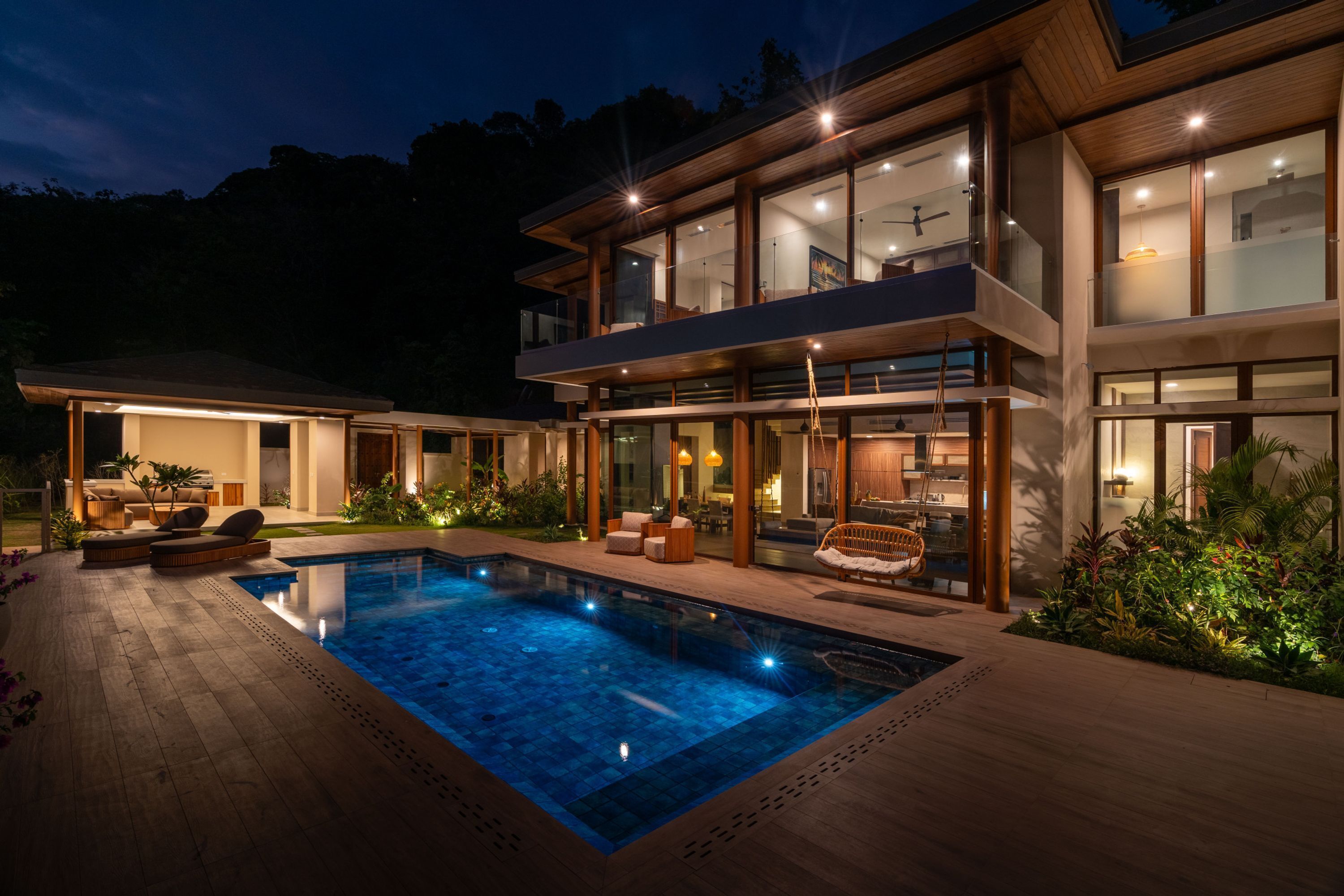 Una casa moderna de dos pisos con piscina, mobiliario exterior y ventanas amplias.