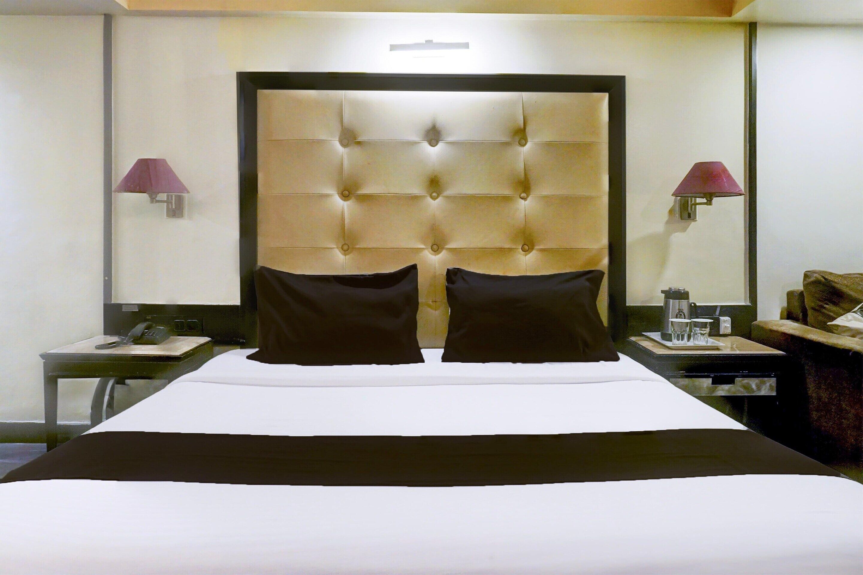 Een hotelkamer met een groot bed, twee nachtkastjes, een lamp en een wandlamp.