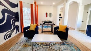 A modern living room with two blue armchairs, a white coffee table, and a dining area in the background. - Radiant Retreat with fitness room (McKinney)