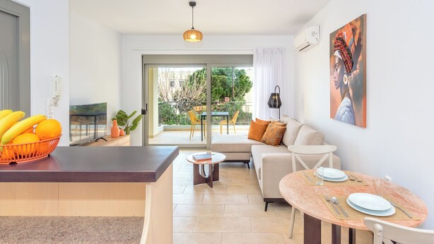 A modern kitchen with a dining area, a sofa, and a table set for two. - Casa Kamara I1 (Kounoupidiana)