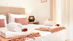 A neatly made bed with rolled towels, a rose, and a macrame throw. - Casa Kamara I1 (Kounoupidiana)