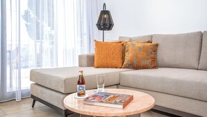 A modern living room with a beige sofa, a round coffee table, a bottle of tea, and a magazine. - Casa Kamara I1 (Kounoupidiana)