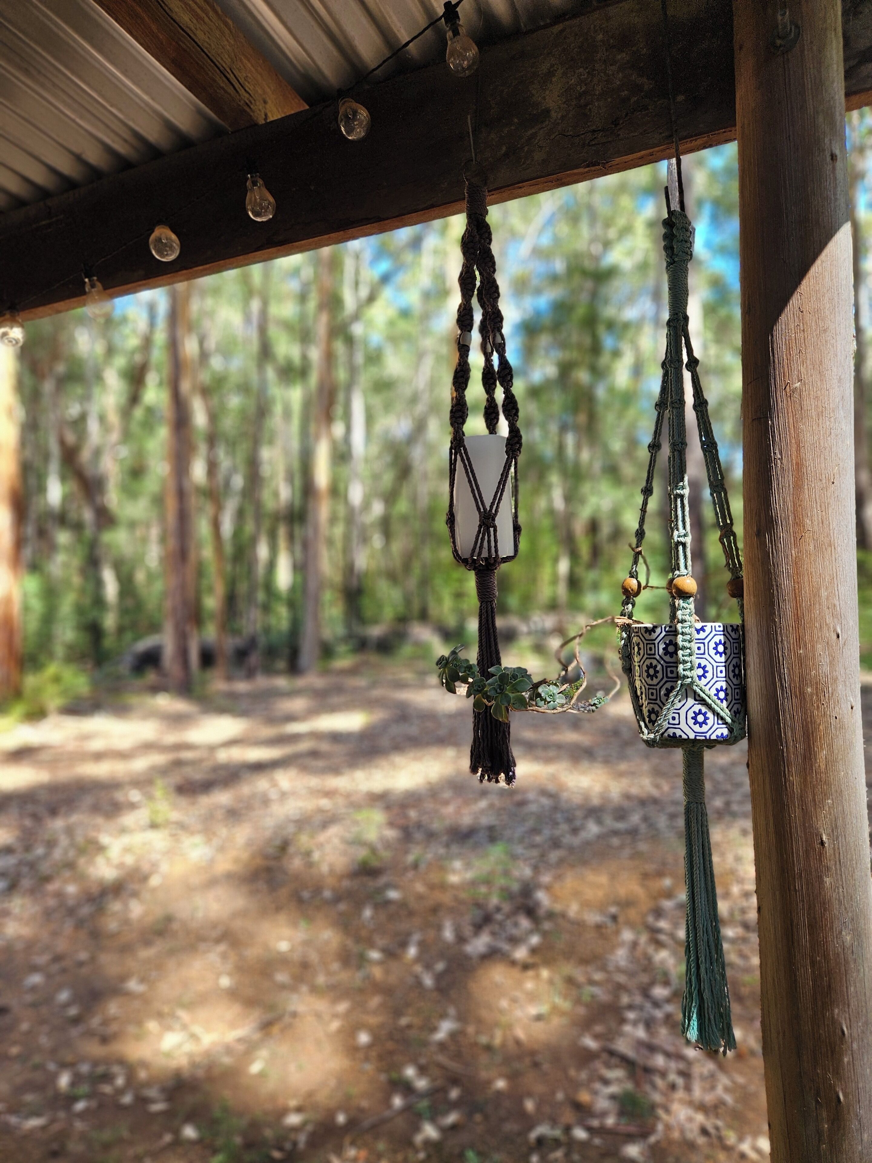 A wooden structure with macramé hangings, including a macramé wall hanging and a macramé bag with a patterned cover.