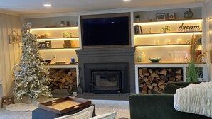 Ein gemütliches Wohnzimmer mit Kamin, Fernseher und Weihnachtstannenbaum.