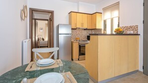 A compact kitchen with wooden cabinets, a built-in microwave, and a small dining area with a glass table and chairs.