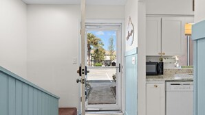 A kitchen with white cabinets, a microwave, and a sign that reads "The Beach Fixes."